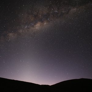 Sternenhimmel über dunklen Hügeln, am Horizont färbt sich der Himmel heller