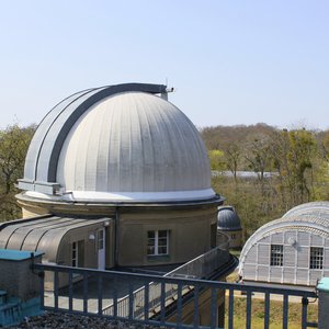 Sicht vom Dach auf eine Seitenkuppel des Humboldthauses. Im Hintergrund ist ein Meridianhaus und eine weitere kleine Teleskopkuppel zu sehen.