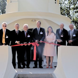 Sieben Personen stehen mit Scheren hinter einem roten Band auf der Tetrasse des Einsteinturms.