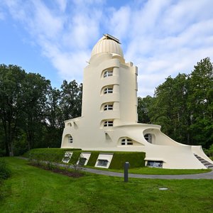 Brightly coloured tower with green grass, surrounded by tall trees