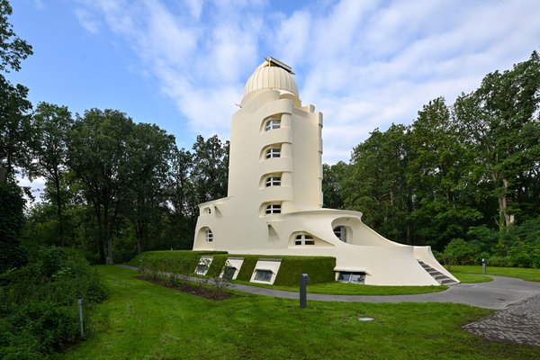 Brightly coloured tower with green grass, surrounded by tall trees