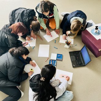 Girls sitting in a circle, drawing something