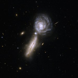 Two galaxies standing close to each other, one seen from the side, the other one face-on. A spiral structure is recognisable in this one.