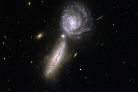 Two galaxies standing close to each other, one seen from the side, the other one face-on. A spiral structure is recognisable in this one.