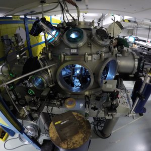 A large experimental setup with several round windows, cables and metal parts in a laboratory room