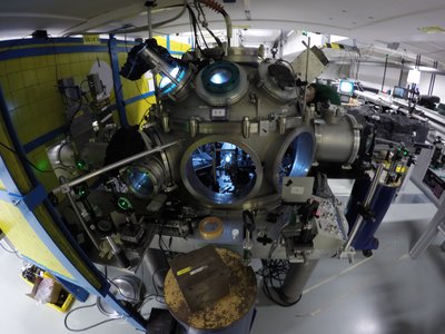 A large experimental setup with several round windows, cables and metal parts in a laboratory room