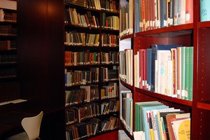 Books in shelves, in the background a small desk with a chair