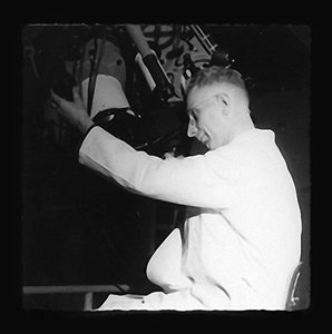 Man in white coat looks through telescope